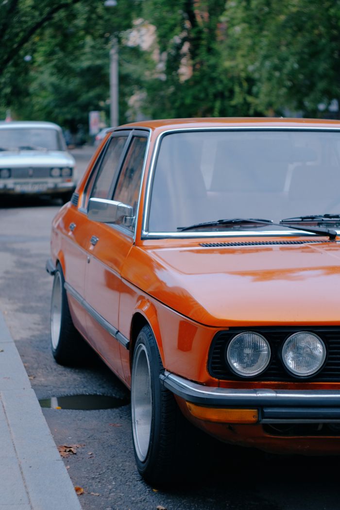 Mastering the First Impression: Your intriguing post title goes here Classic orange car parked on a street in Kyiv, Ukraine, showcasing vintage automotive design.