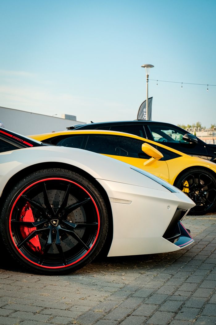 Offerings Two luxury sports cars parked side by side in an urban area under clear skies.