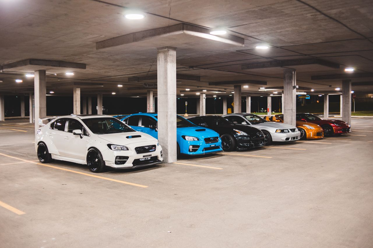 Offerings Bright new expensive automobiles placed on parking lot under concrete roof with bright lights